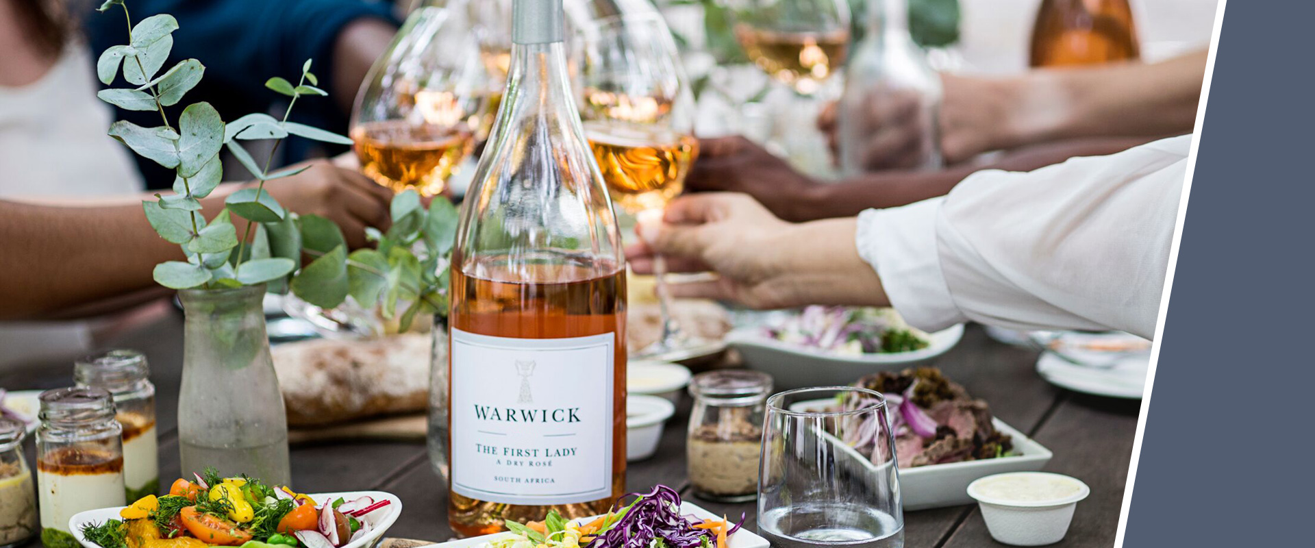 Bottle of rosé wine on a laid table with various dishes and salads